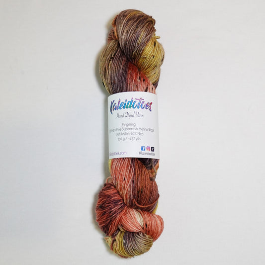 Hand-dyed tweed fingering weight yarn in burnished coral, ochre gold, earthy olive and smoky plum-brown with black tweed flecks.