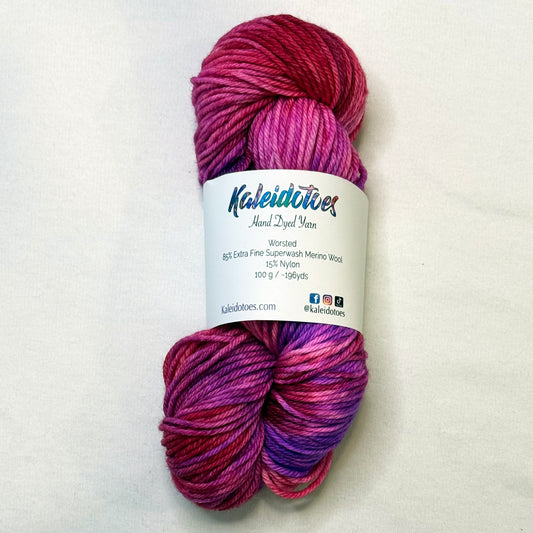 Hand-dyed yarn in a mix of bright red, pink, and purple tones