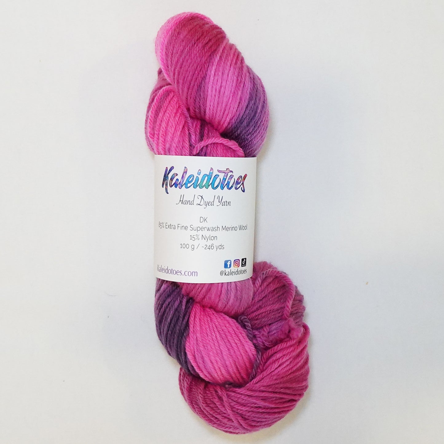 Hand-dyed DK weight yarn in hot pink, deep mauve, and dusty amethyst - vivid, moody, and richly variegated throughout.