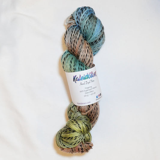 Hand-dyed fingering weight yarn in sand, sage, sky blue, and olive with black threading throughout on a zebra base.