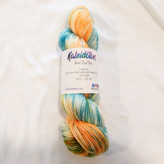 Hand-dyed fingering weight yarn in soft aqua, teal, golden orange, and cream with fluid variegated movement inspired by koi fish.