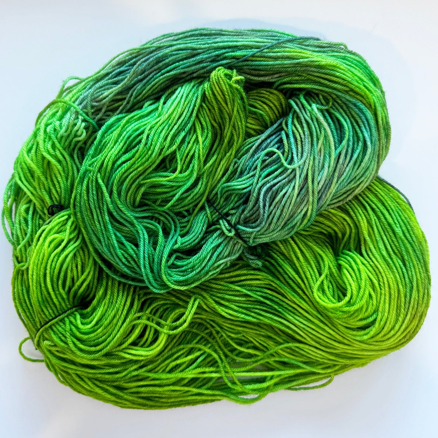 Mossy Mirage fingering weight sock yarn in shades of light green, emerald, and earthy tones