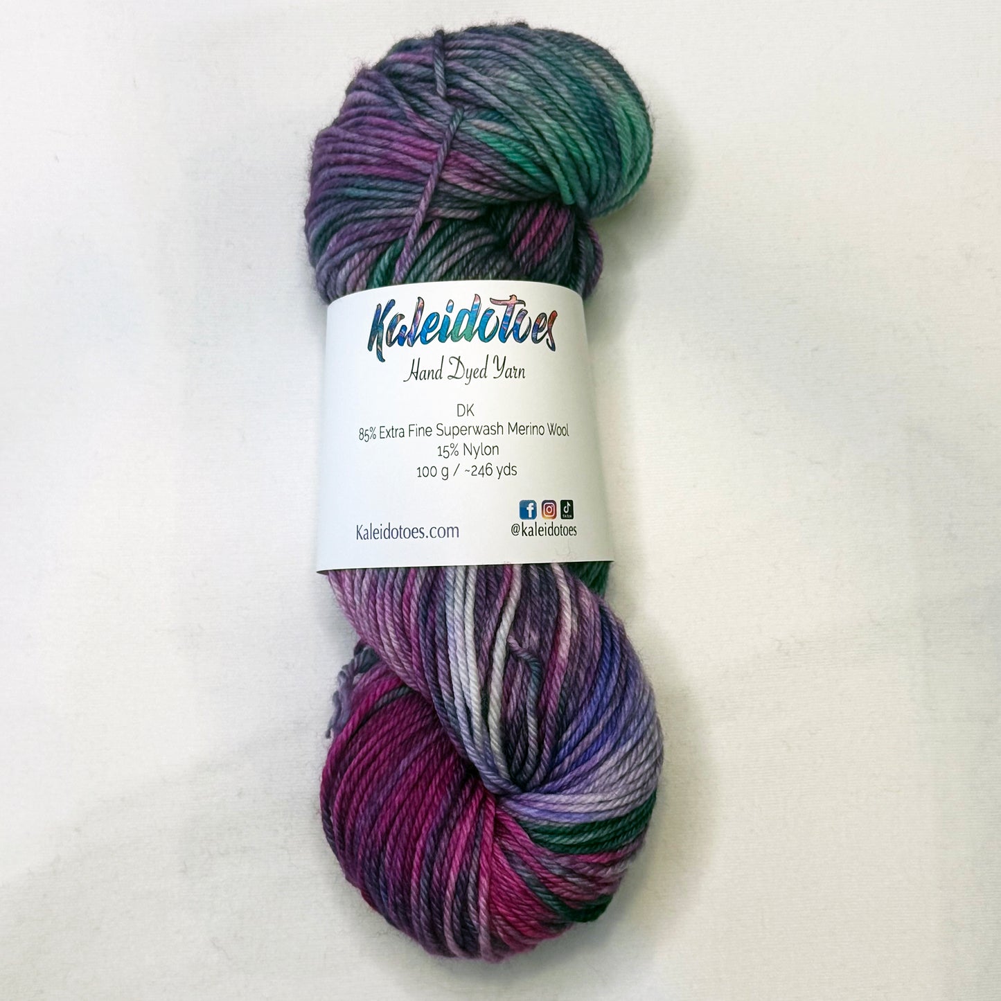 Hand-dyed yarn in deep violet, teal, mint, and soft white — moody, elegant, and softly luminous.