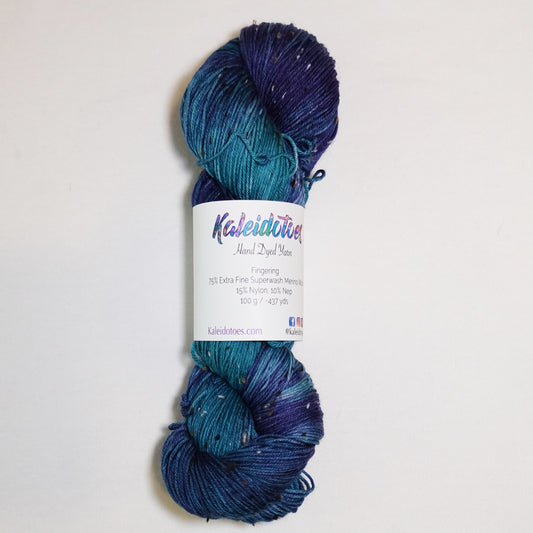 Hand-dyed tweed fingering weight yarn in teal green, rich blue and deep navy with contrasting tweed flecks.