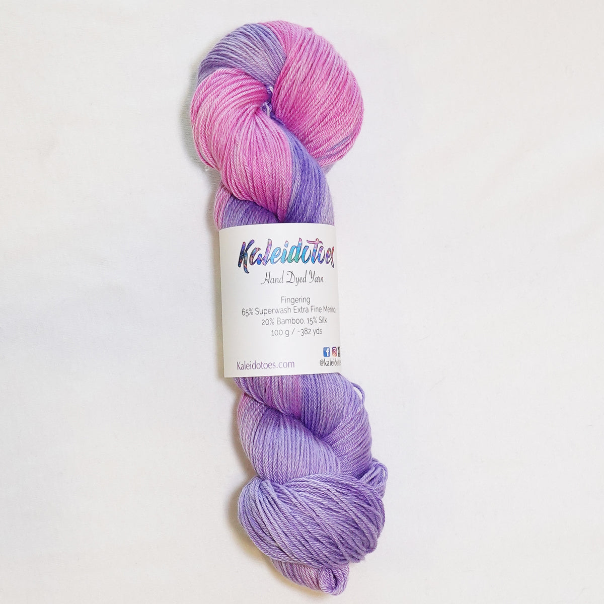 Hand-dyed fingering weight yarn in petal pink and soft lilac with a soft tonal fade.