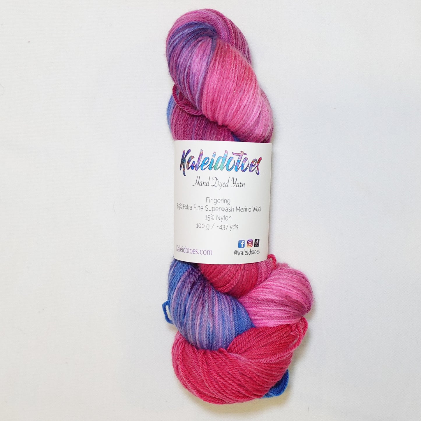 Hand-dyed fingering weight yarn in hot magenta, deep berry, and periwinkle blue with rich saturated color transitions throughout.