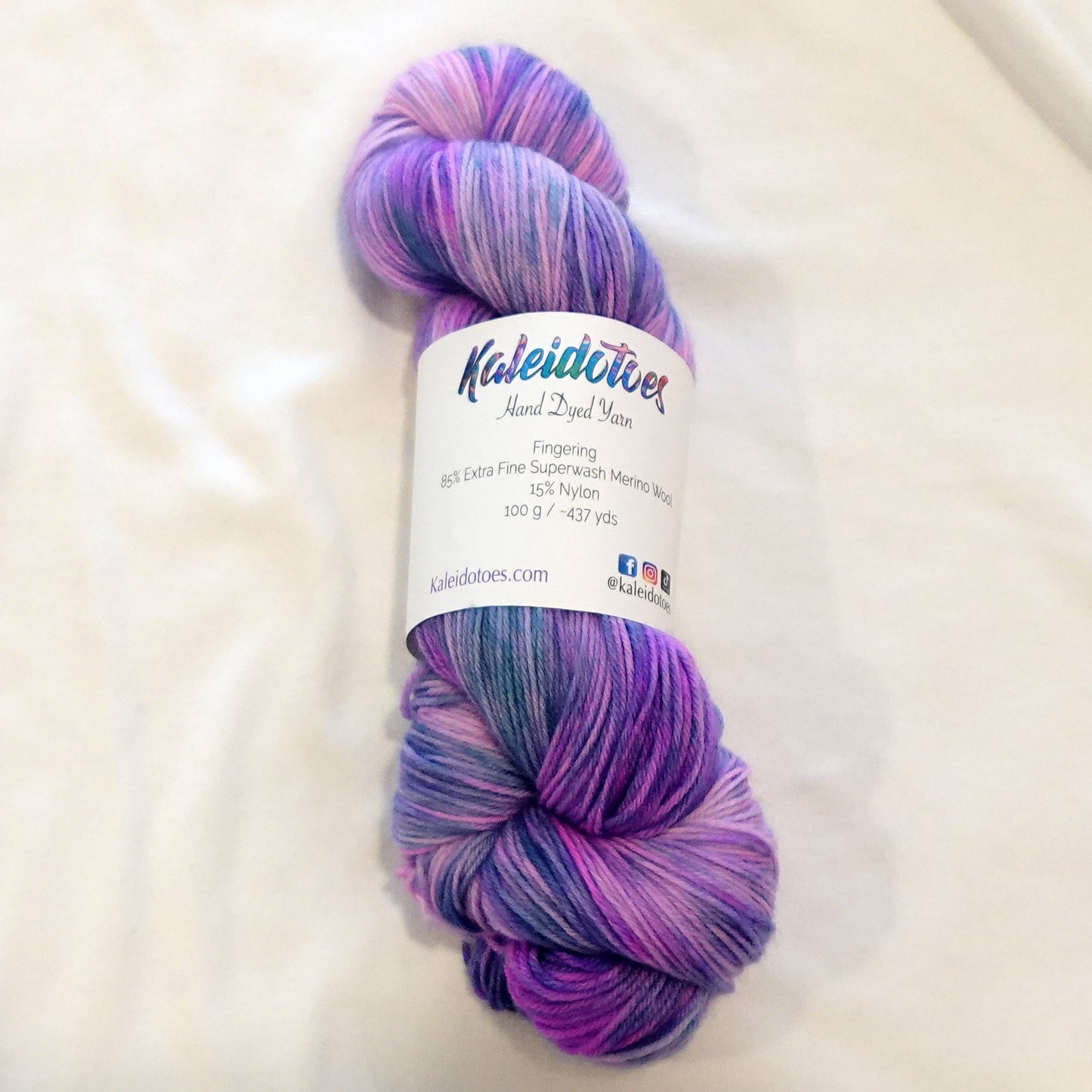Hand-dyed fingering weight yarn in lavender, orchid, violet, and cool periwinkle with flowing variegated movement.