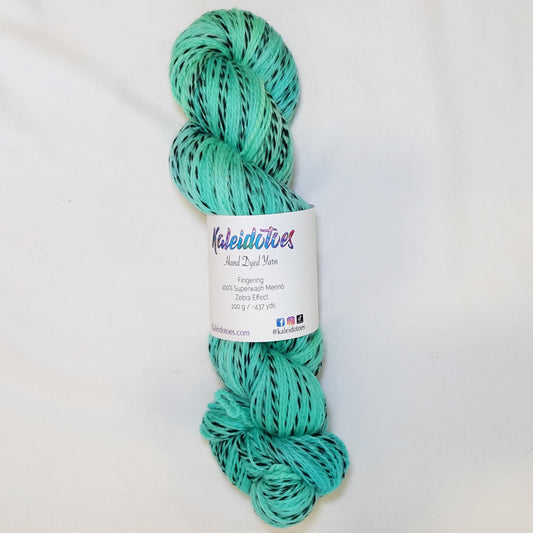 Hand-dyed fingering weight yarn in bright turquoise-teal with aqua and green undertones and black twisted through throughout.