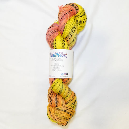 Hand-dyed fingering weight yarn in bright lemon yellow, warm peach, and coral with black twisted through throughout.