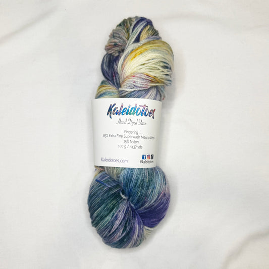 Hand-dyed yarn in soft blues, green, and pink and yellow speckles — light, floral, and garden-inspired.