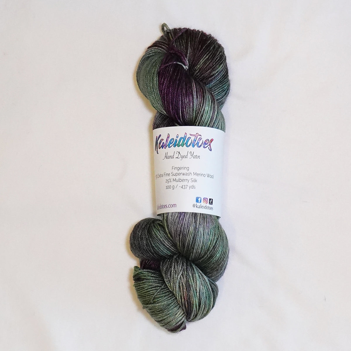 Hand-dyed fingering weight yarn in cactus green, blue-green, olive, and deep aubergine tones.