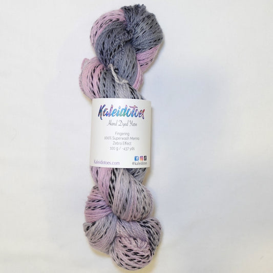 Hand-dyed fingering weight yarn in dusty pink, mauve, and deep blue-grey with black twisted through throughout.