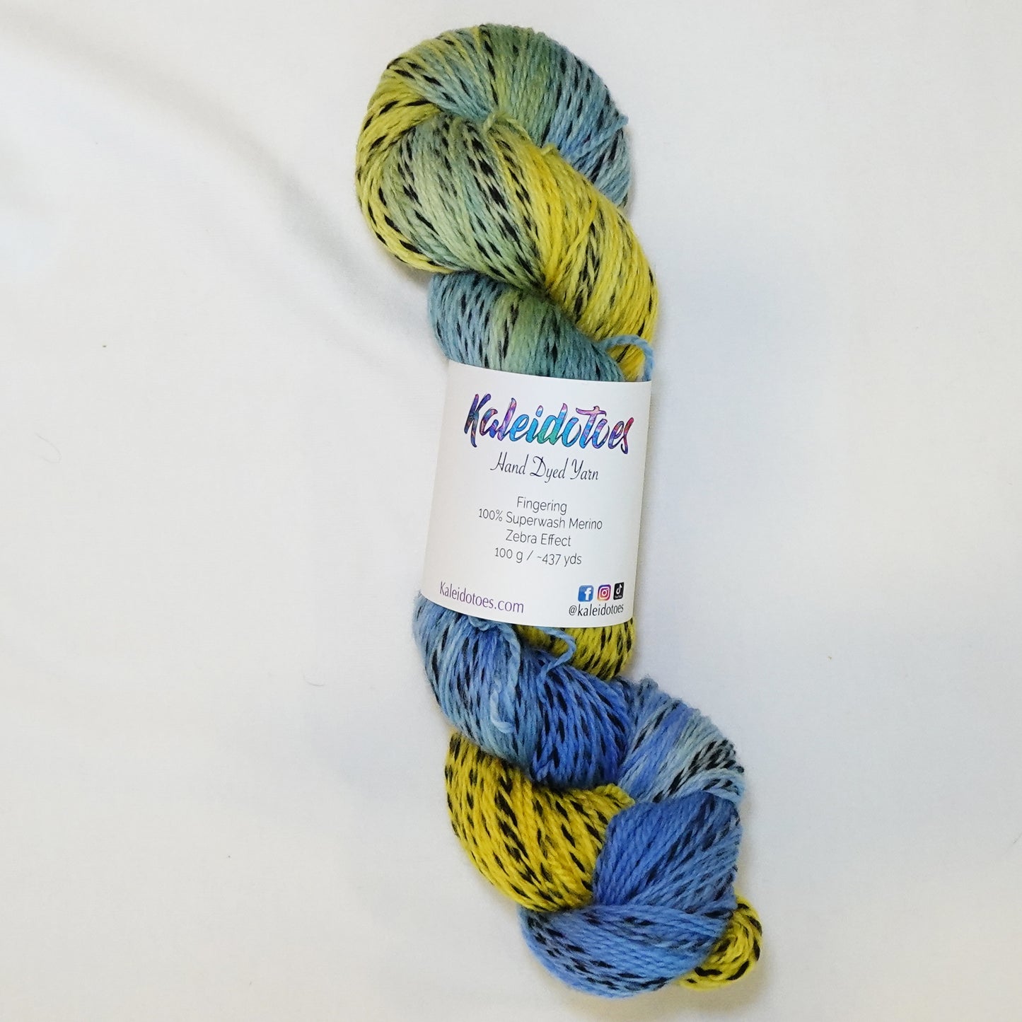 Hand-dyed fingering weight yarn in sunflower yellow and cornflower blue with black twisted through and a soft sage-green where the colors meet.