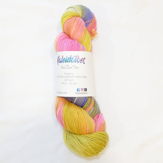 Hand-dyed yarn in vibrant yellow, peach, coral, hot pink, violet, and chartreuse tones — layered and shifting like a classic jawbreaker candy.