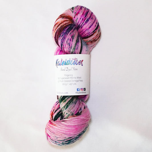 Hand-dyed fingering weight yarn in pink with deep evergreen sections and orange and violet speckles throughout.