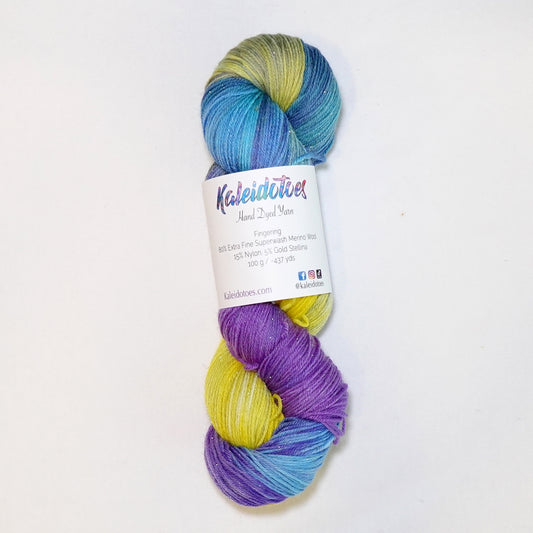 Hand-dyed yarn in shifting yellow, violet, and teal tones with gold metallic running throughout — bold, festive, and full of movement.