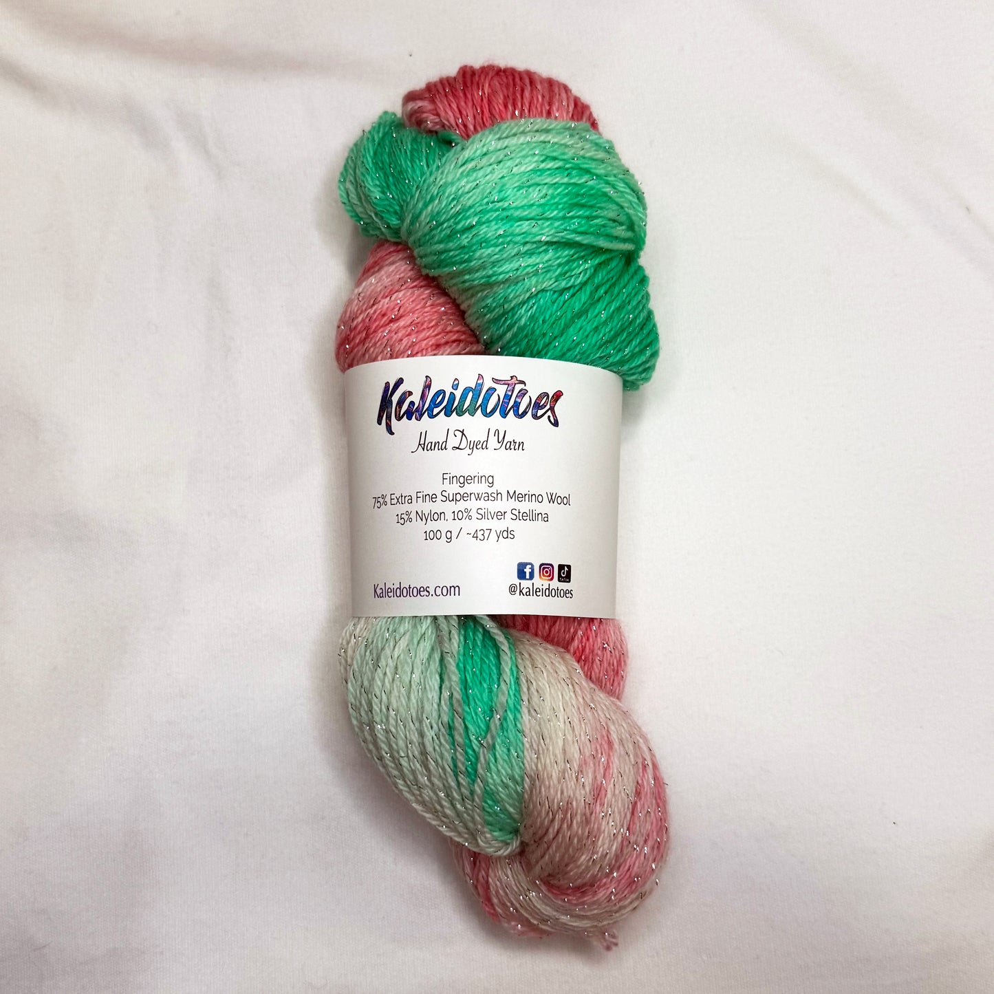 Hand-dyed yarn in mint green, soft pinks, and ivory tones with subtle silver metallic throughout.