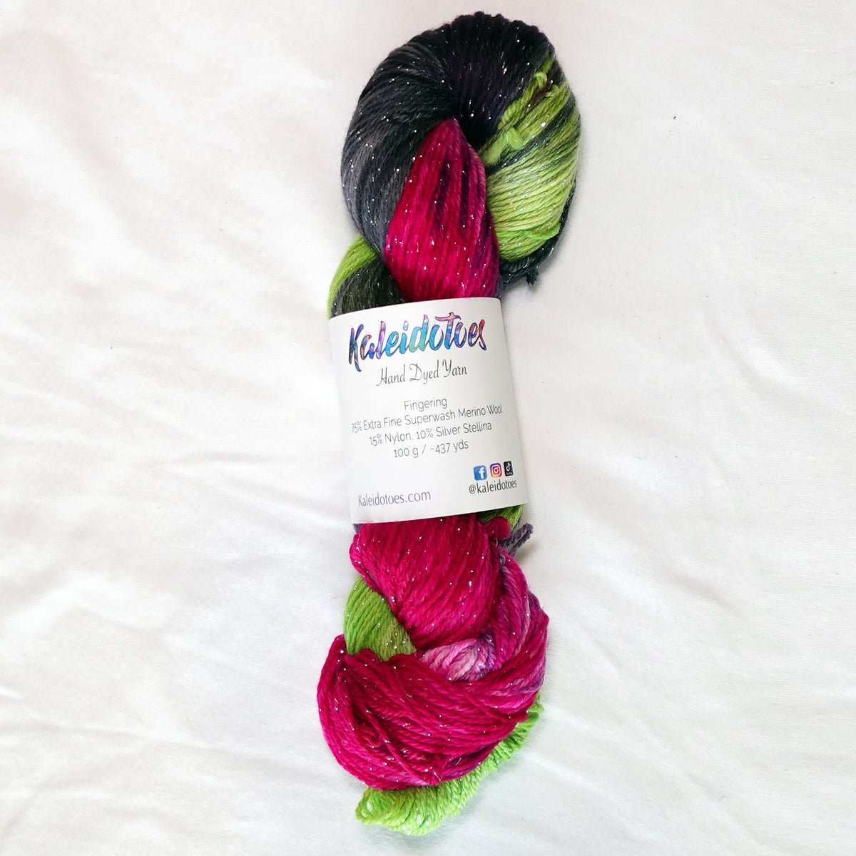 Practically Magic hand-dyed fingering weight yarn in brilliant fuchsia, vivid green and smoky charcoal with a fine silver metallic thread.