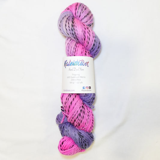 Hand-dyed fingering weight yarn in hot pink and soft lilac with black twisted through and a muted orchid blend where the colors meet.