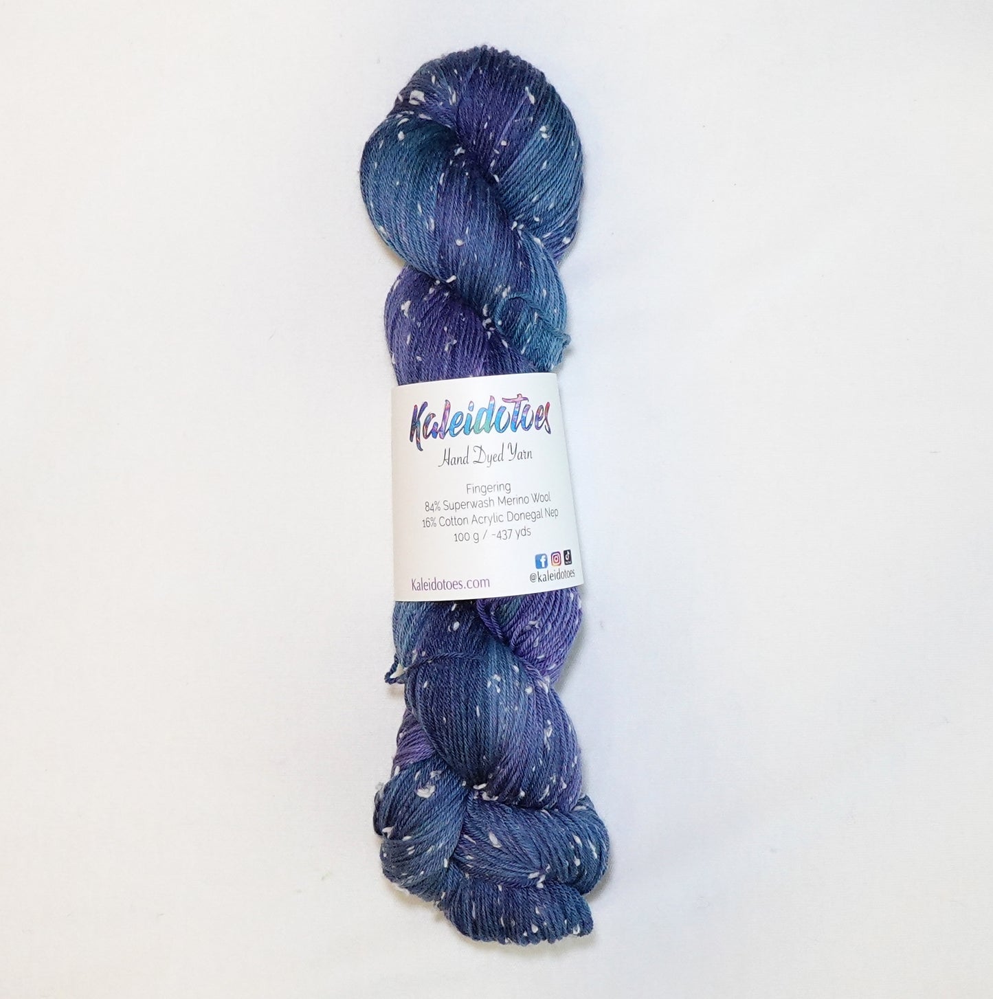 Hand-dyed yarn in shades of deep blue, indigo, and violet with soft white flecks scattered throughout — moody, layered, and reminiscent of a star-filled night sky.