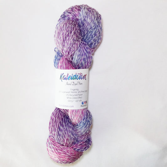Hand-dyed white zebra base fingering weight yarn in lilac, orchid pink, and periwinkle blue with white plied throughout.