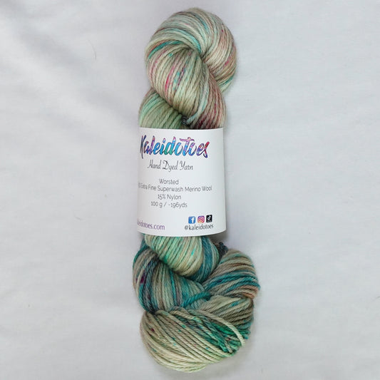 Hand-dyed worsted weight yarn in warm sand with teal, coral, and pink speckles throughout.