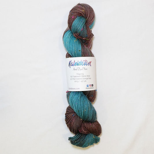 Hand-dyed fingering weight yarn in deep chocolate and bright teal with charcoal transitions and multicolor confetti flecks throughout.