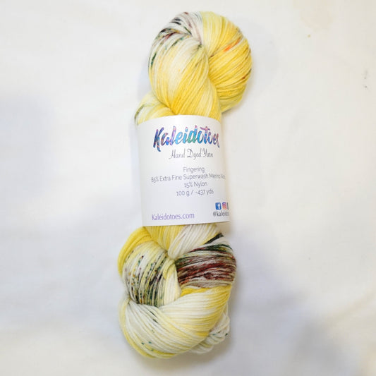 Hand-dyed yarn in rich sunflower yellow with earthy green and brown speckles — warm, grounded, and inspired by wild sunflower fields.