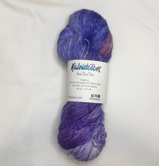 Hand-dyed yarn in grape, berry, lilac, and violet tones with subtle silver metallic throughout.
