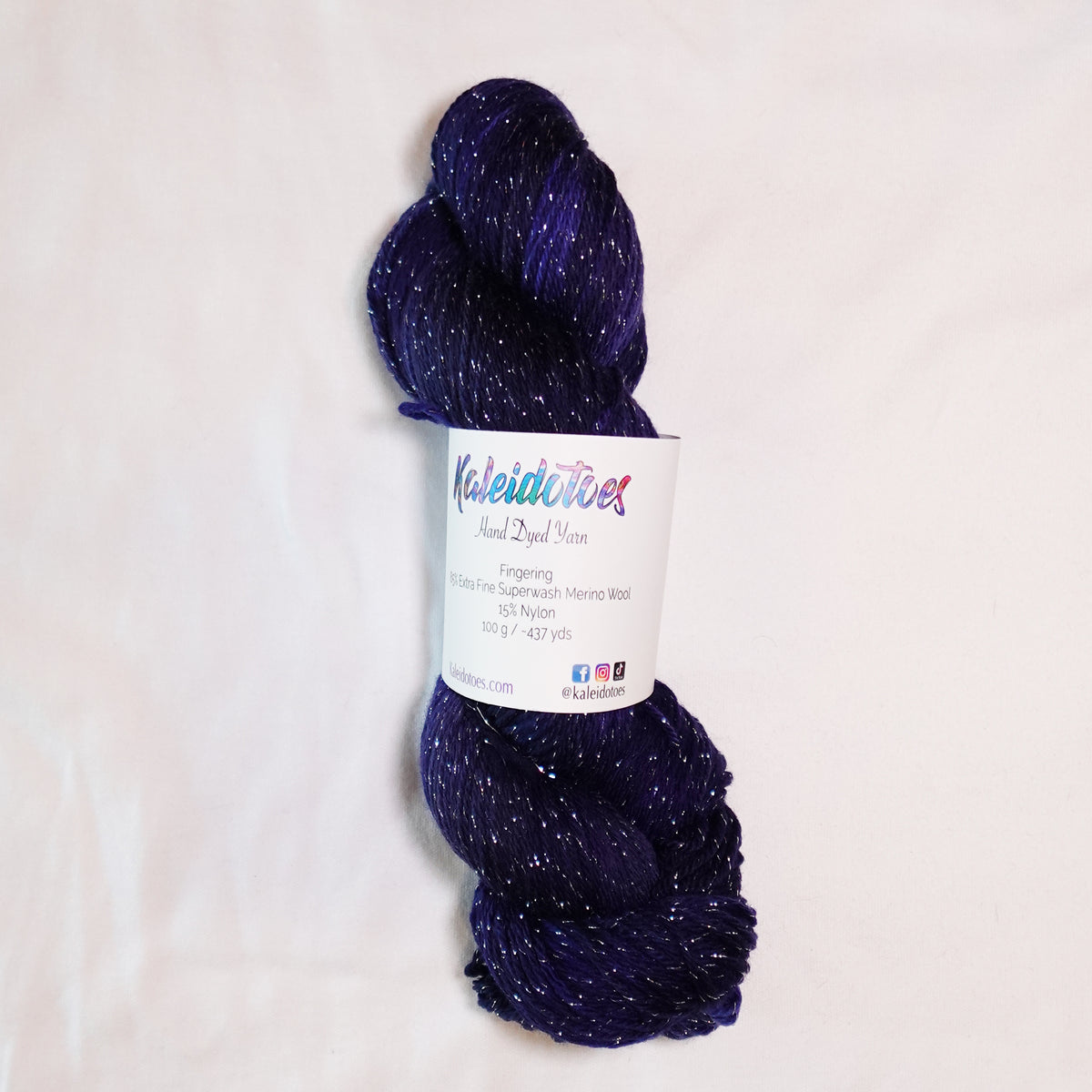 Hand-dyed silver metallic fingering weight yarn in deep navy, violet, and near-black tones with silver sparkle.