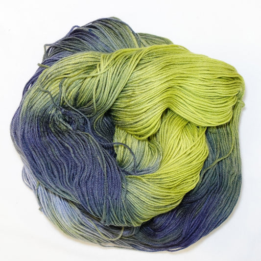 Hand-dyed fingering weight yarn in chartreuse green, olive, slate blue, and deep indigo with smooth color transitions throughout.