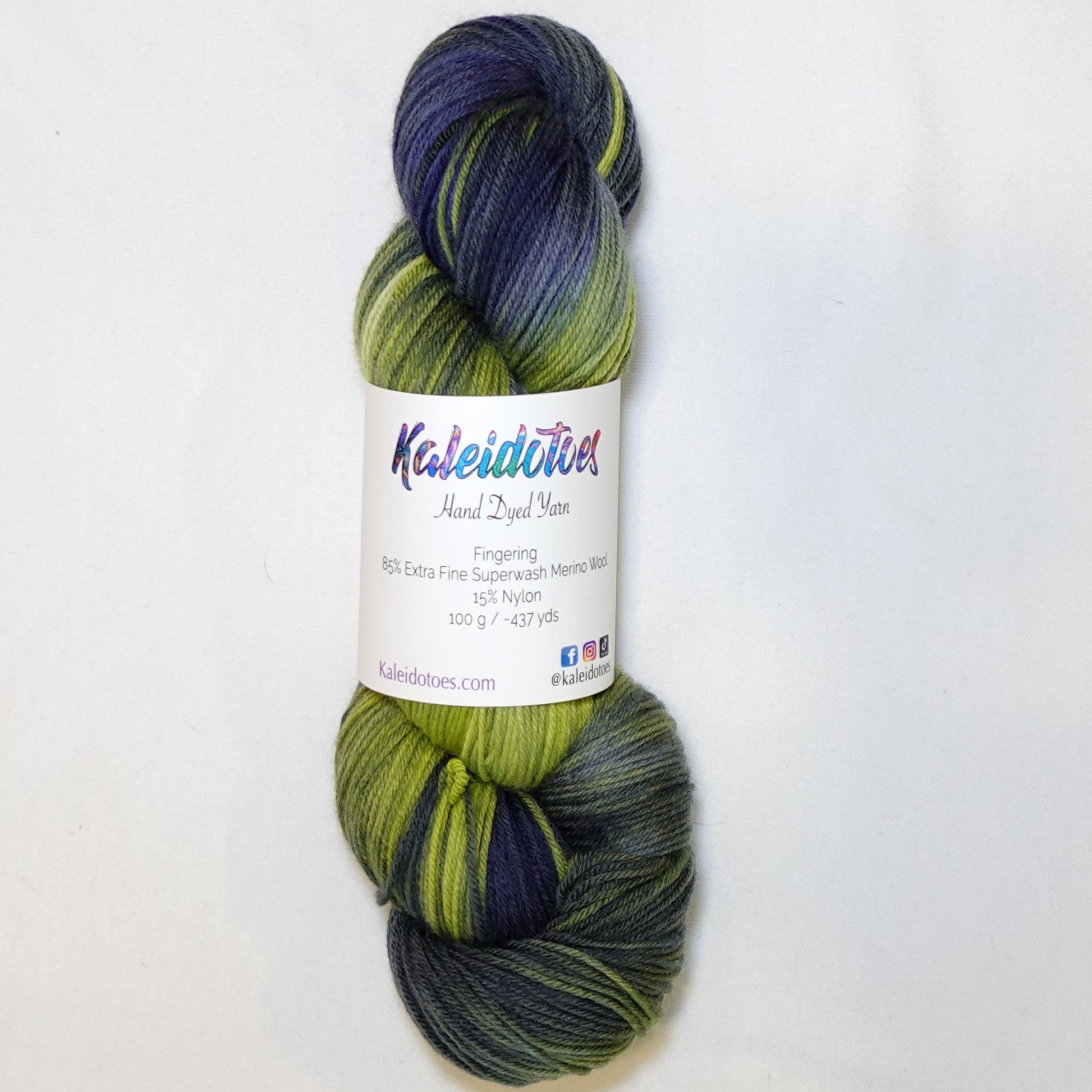 Hand-dyed fingering weight yarn in chartreuse green, olive, slate blue, and deep indigo with smooth color transitions throughout.