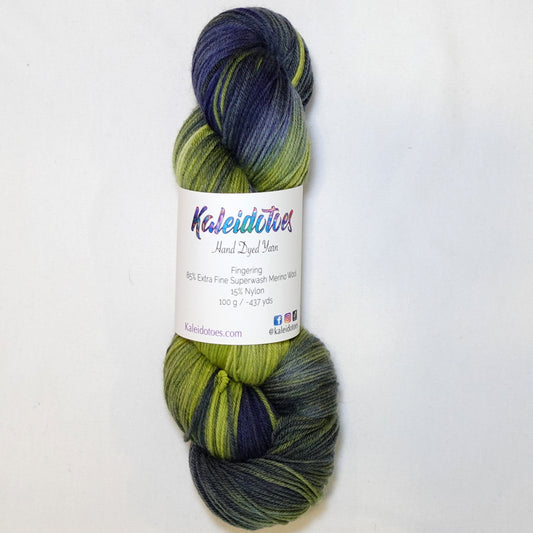Hand-dyed fingering weight yarn in chartreuse green, olive, slate blue, and deep indigo with smooth color transitions throughout.