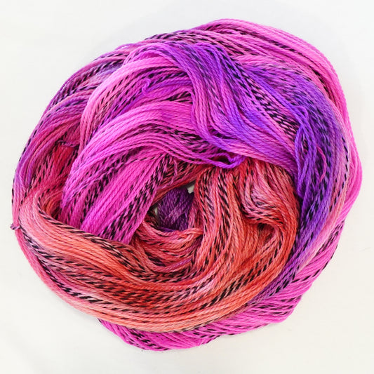Hand-dyed fingering weight yarn in coral, hot magenta, and electric violet with black threading throughout on a zebra base.