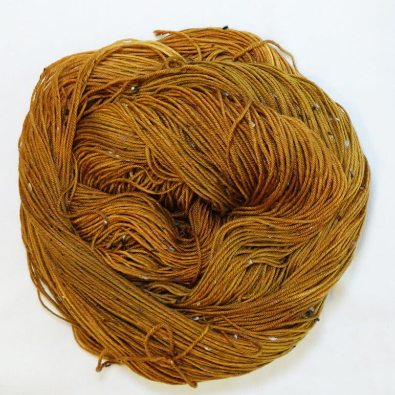Hand-dyed tweed fingering weight yarn in whiskey gold, aged amber, caramel and toasted brown with tweed flecks.
