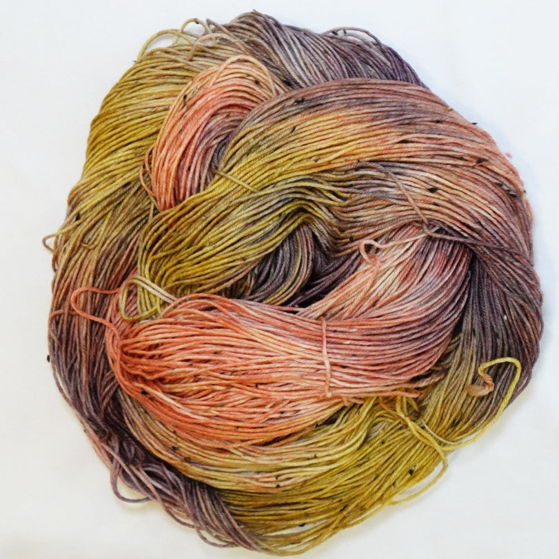 Hand-dyed tweed fingering weight yarn in burnished coral, ochre gold, earthy olive and smoky plum-brown with black tweed flecks.