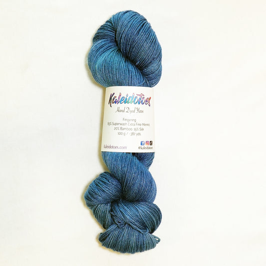 Hand-dyed fingering weight yarn in faded denim blue with lighter worn tones and deeper indigo throughout.
