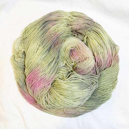 Hand-dyed skein of yarn in soft orchid pink and tonal sage greens, inspired by a blooming cactus flower in the desert.