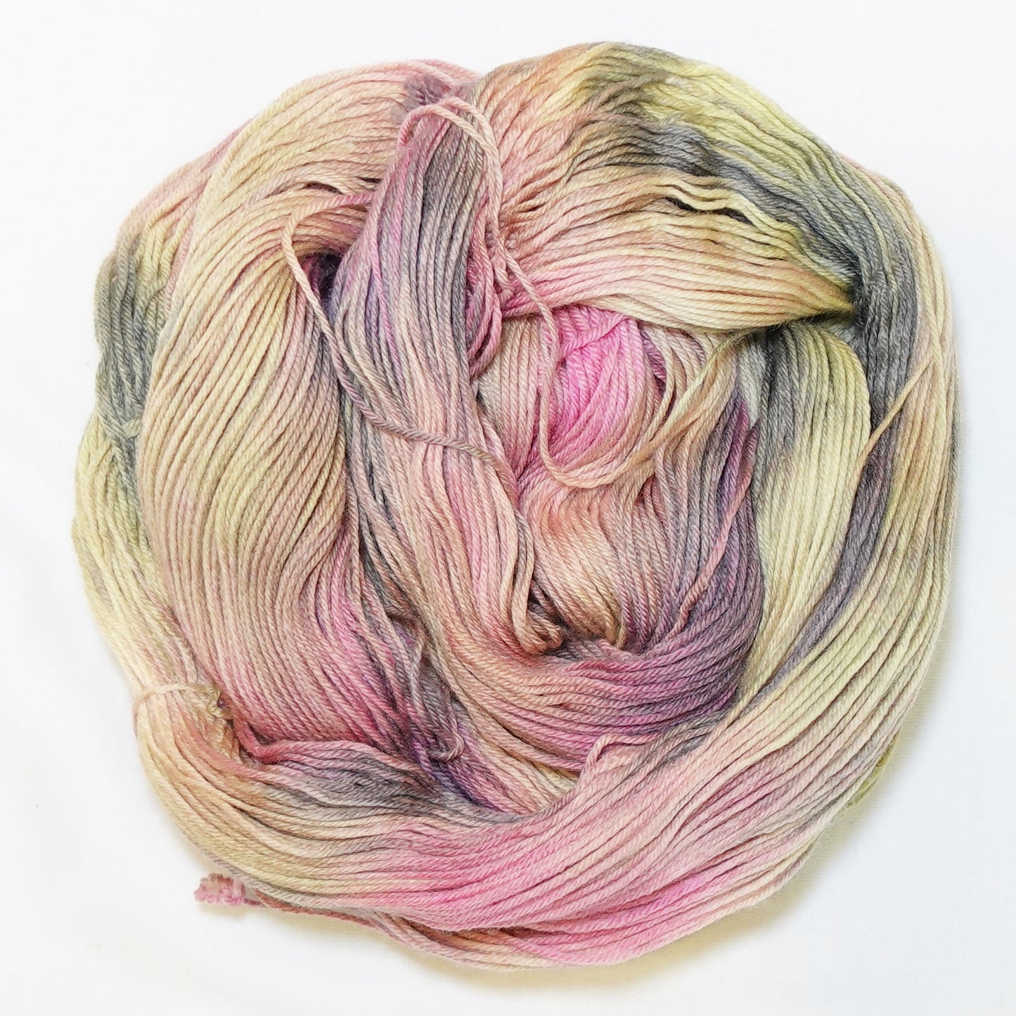 Hand-dyed fingering weight yarn in dusty rose, golden straw, muted olive, and weathered grey-brown with soft blended color transitions throughout.