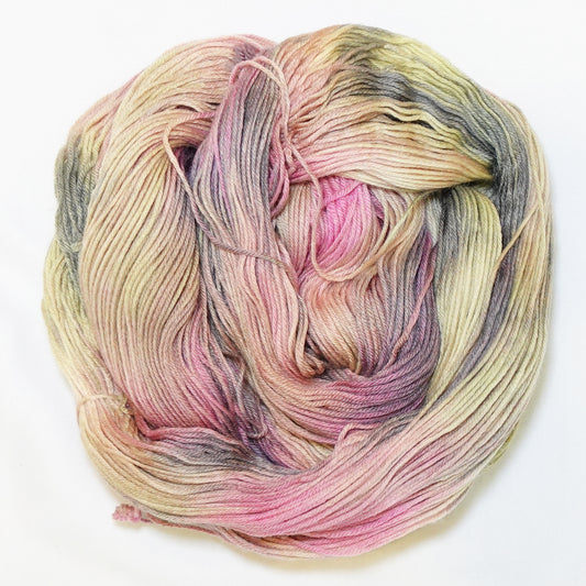 Hand-dyed fingering weight yarn in dusty rose, golden straw, muted olive, and weathered grey-brown with soft blended color transitions throughout.