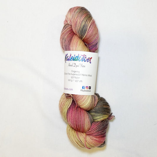 Hand-dyed fingering weight yarn in dusty rose, golden straw, muted olive, and weathered grey-brown with soft blended color transitions throughout.