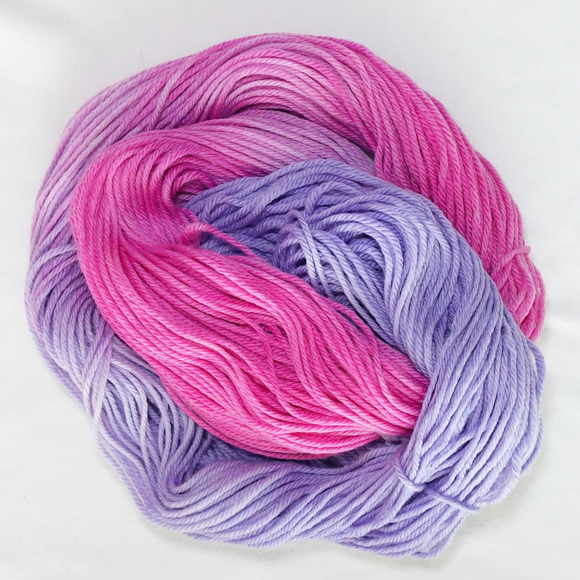 Hand-dyed worsted weight yarn in deep pink, blush, lilac, and soft lavender with smooth gradient transitions throughout.