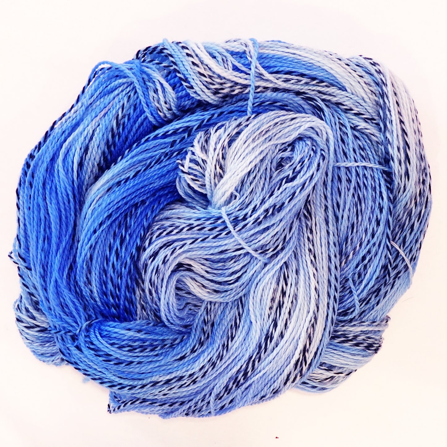 Hand-dyed fingering weight yarn in sand, sage, sky blue, and olive with black threading throughout on a zebra base.