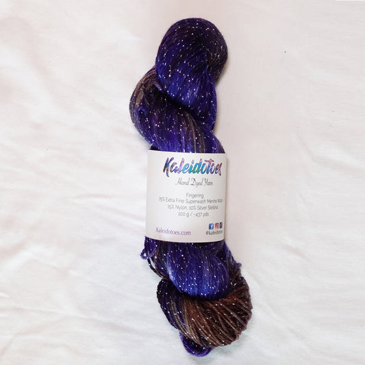 Decadent Behavior hand-dyed fingering weight yarn in saturated violet and deep chocolate brown with rich plum tones and a fine silver metallic thread.