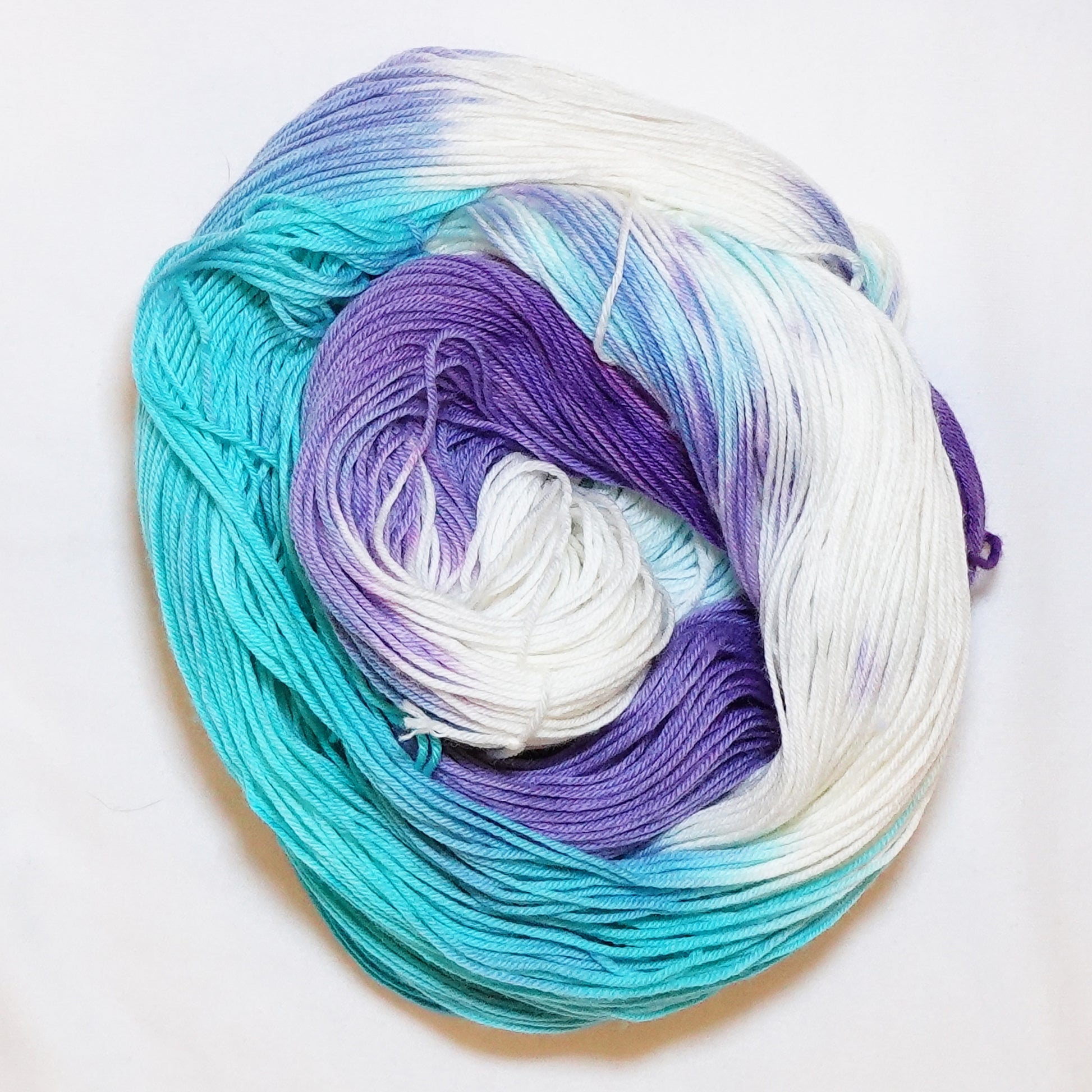 Hand dyed fingering weight sock yarn in bright aqua, hyacinth purple, and white, hand dyed by Kaleidotoes in Las Vegas