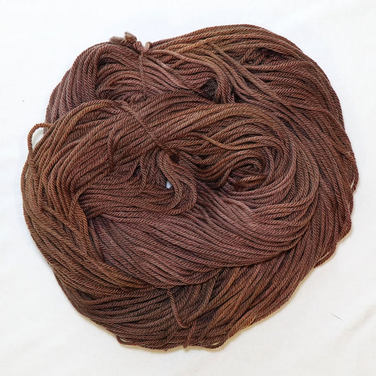 Hand-dyed worsted weight yarn in warm faded chestnut brown tones with gentle sun-softened tonal variation throughout.