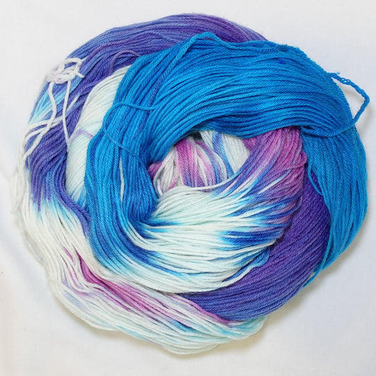 Hand-dyed fingering weight yarn in brilliant blue, soft mint, white, deep violet, and pink with swirling tie-dye color movement throughout.