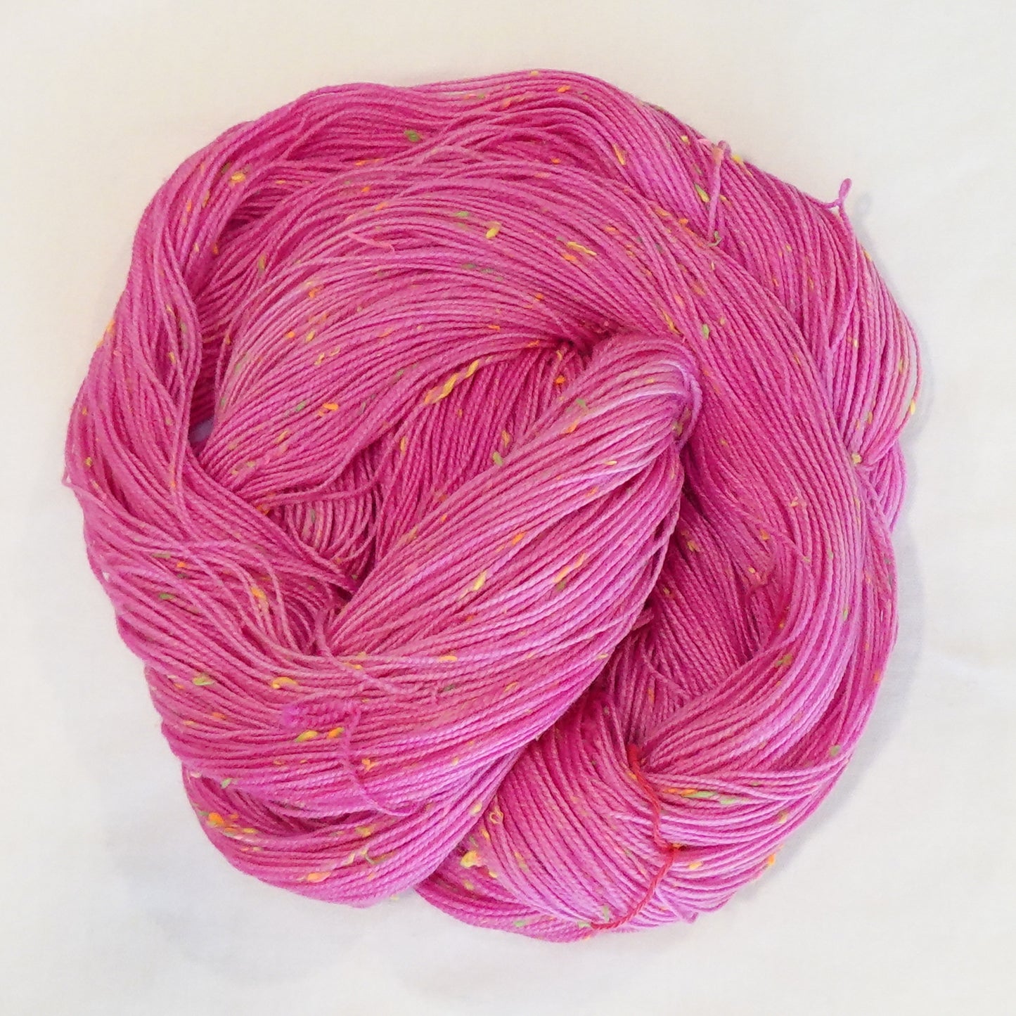 Hand-dyed yarn in vibrant pink tones with bright neon flecks — bold, playful, and full of lively movement.