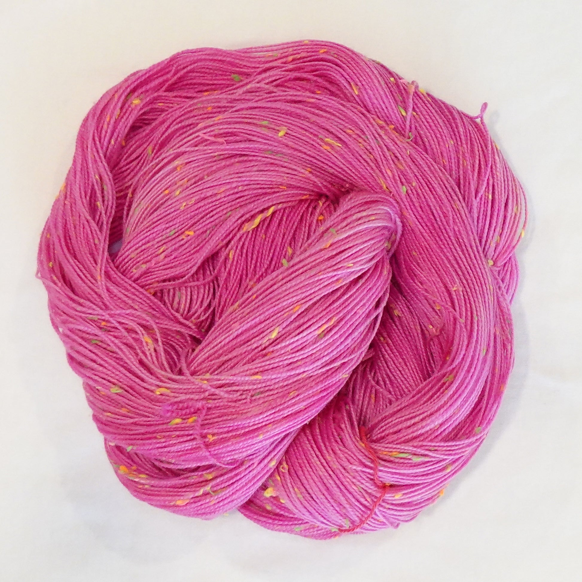 Hand-dyed yarn in vibrant pink tones with bright neon flecks — bold, playful, and full of lively movement.