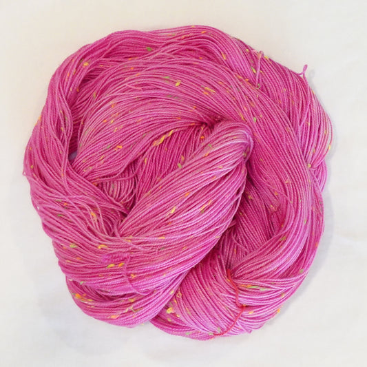 Hand-dyed yarn in vibrant pink tones with bright neon flecks — bold, playful, and full of lively movement.